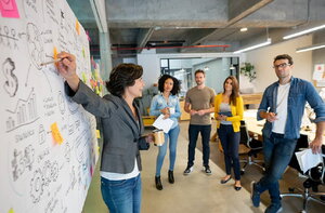 A worker points at a whiteboard