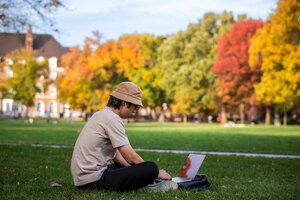 Student sitting on the grass on the Main Quad with laptop open